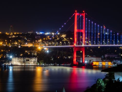 Free Stunning night view of the illuminated Bosphorus Bridge in Istanbul, reflecting on the calm waters below. Stock Photo
