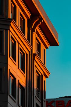 A city building facade illuminated by warm sunlight against a clear blue sky.