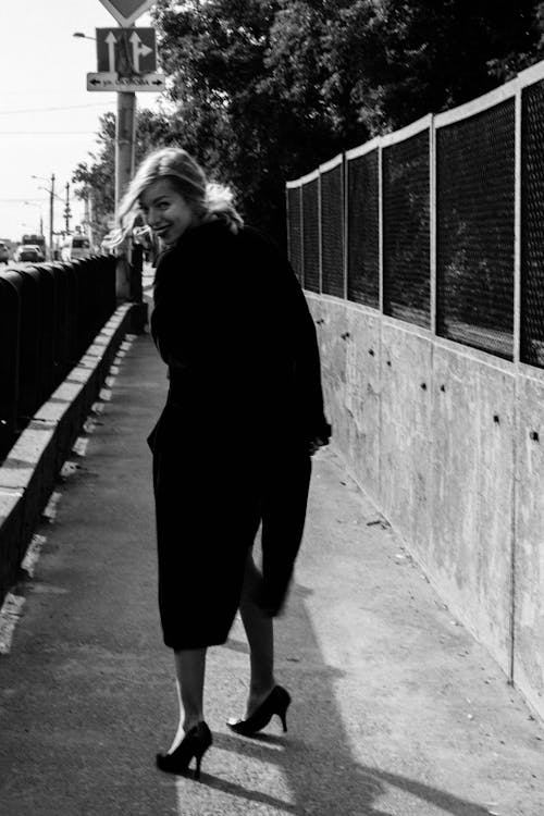 Monochrome Shot of a Woman Standing on a Sidewalk
