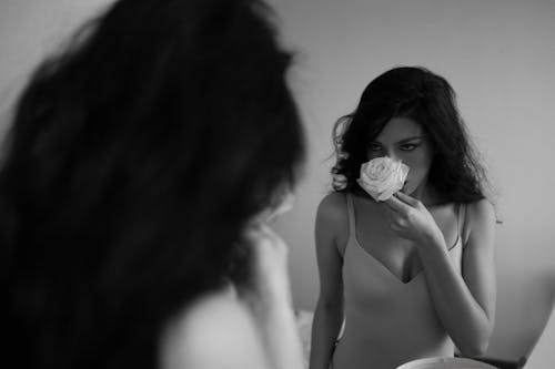 Woman Smelling Rose in Front of Mirror