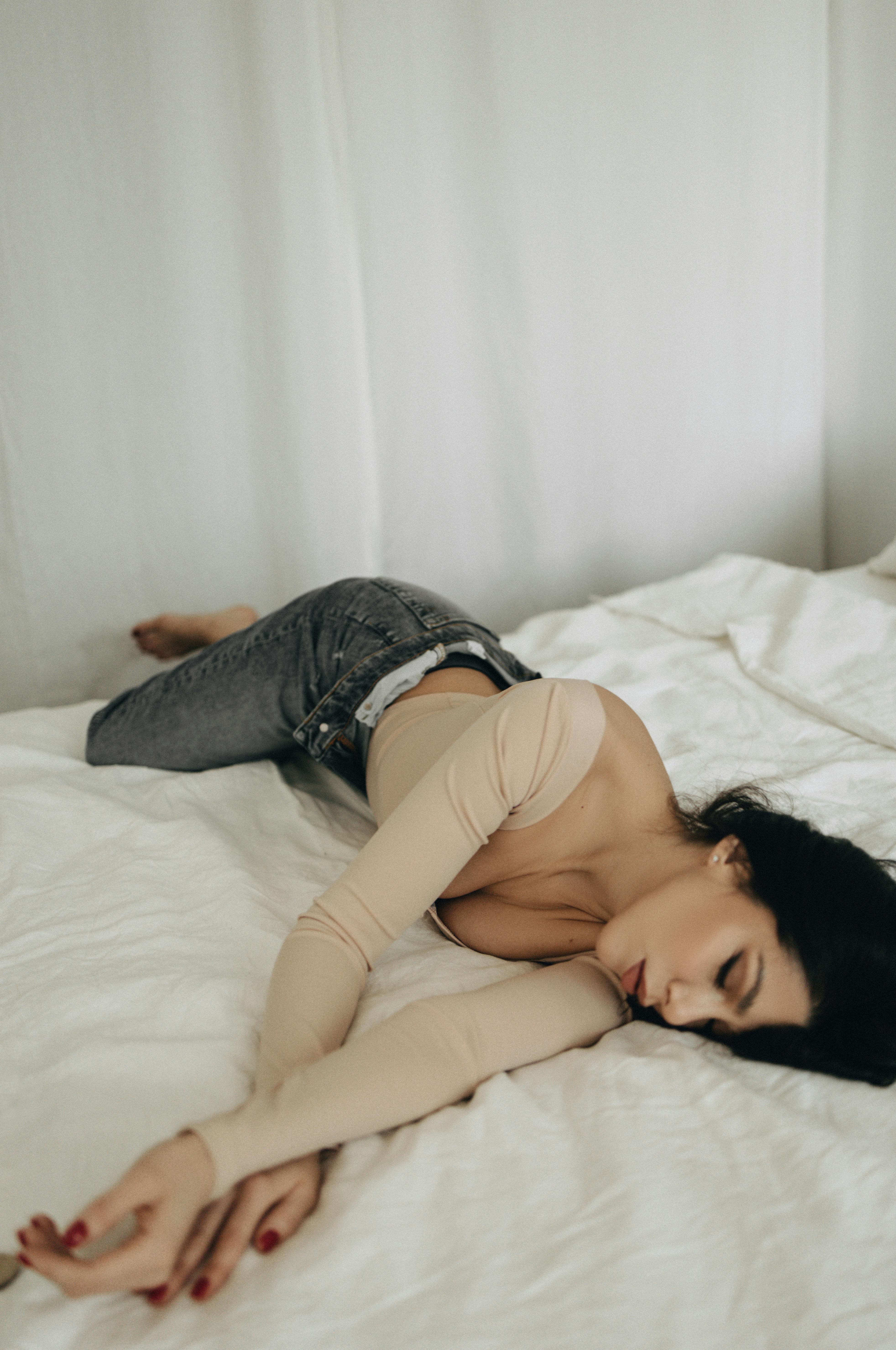 A woman relaxing on a white bed, capturing a moment of serene rest.