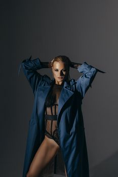 Striking studio portrait of a woman in lingerie and trench coat, exuding confidence and style.