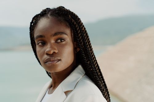 Free A captivating portrait of a woman with braided hair standing against a serene seaside backdrop. Stock Photo