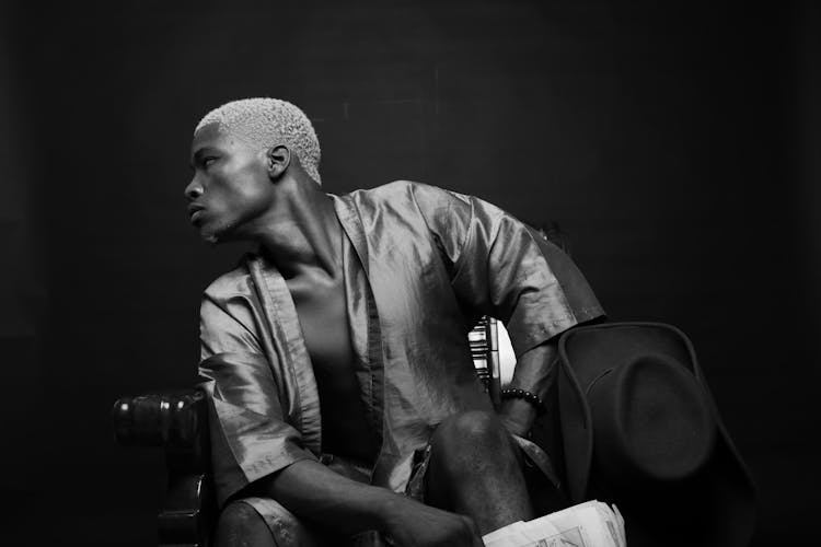 Young Man Sitting In Chair In Darkness And Leaning Aside