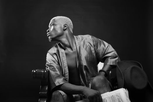 Young man sitting in chair in darkness and leaning aside
