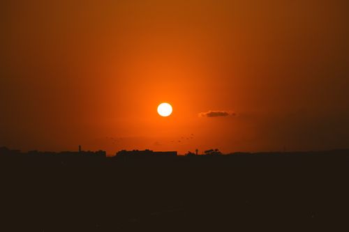 Free Stunning orange sunset with silhouetted skyline creating a serene and tranquil atmosphere. Stock Photo
