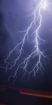 Intense lightning bolt illuminating a dark night sky during a powerful thunderstorm.