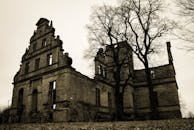 在阴沉的天空下，周围环绕着落叶的树木，探索一座历史悠久的废弃城堡，其美丽令人难忘