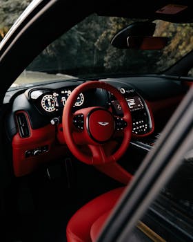 Sleek interior view of a luxury car with red leather accents and high-tech dashboard.