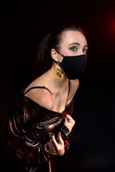 Portrait of a stylish woman wearing a mask and a barcode tattoo on a black background.