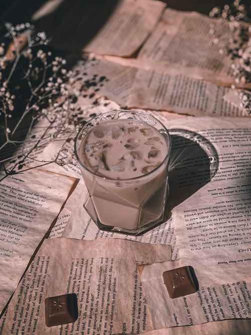 Free Artistic setup of iced coffee and chocolates on vintage papers, creating a warm, nostalgic atmosphere. Stock Photo