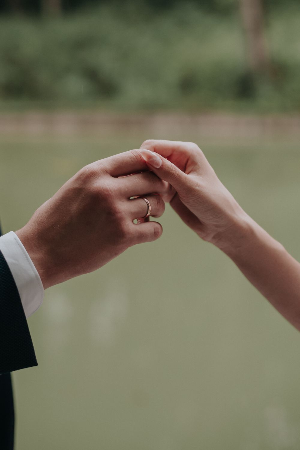 A couple's hands resting together, both wearing wedding rings