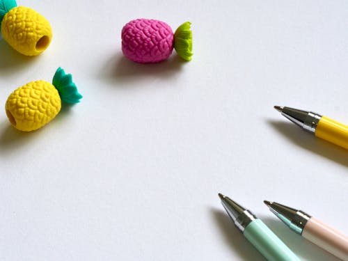 Closeup Photo of Three Assorted-color Pens Near Pineapples Miniatures