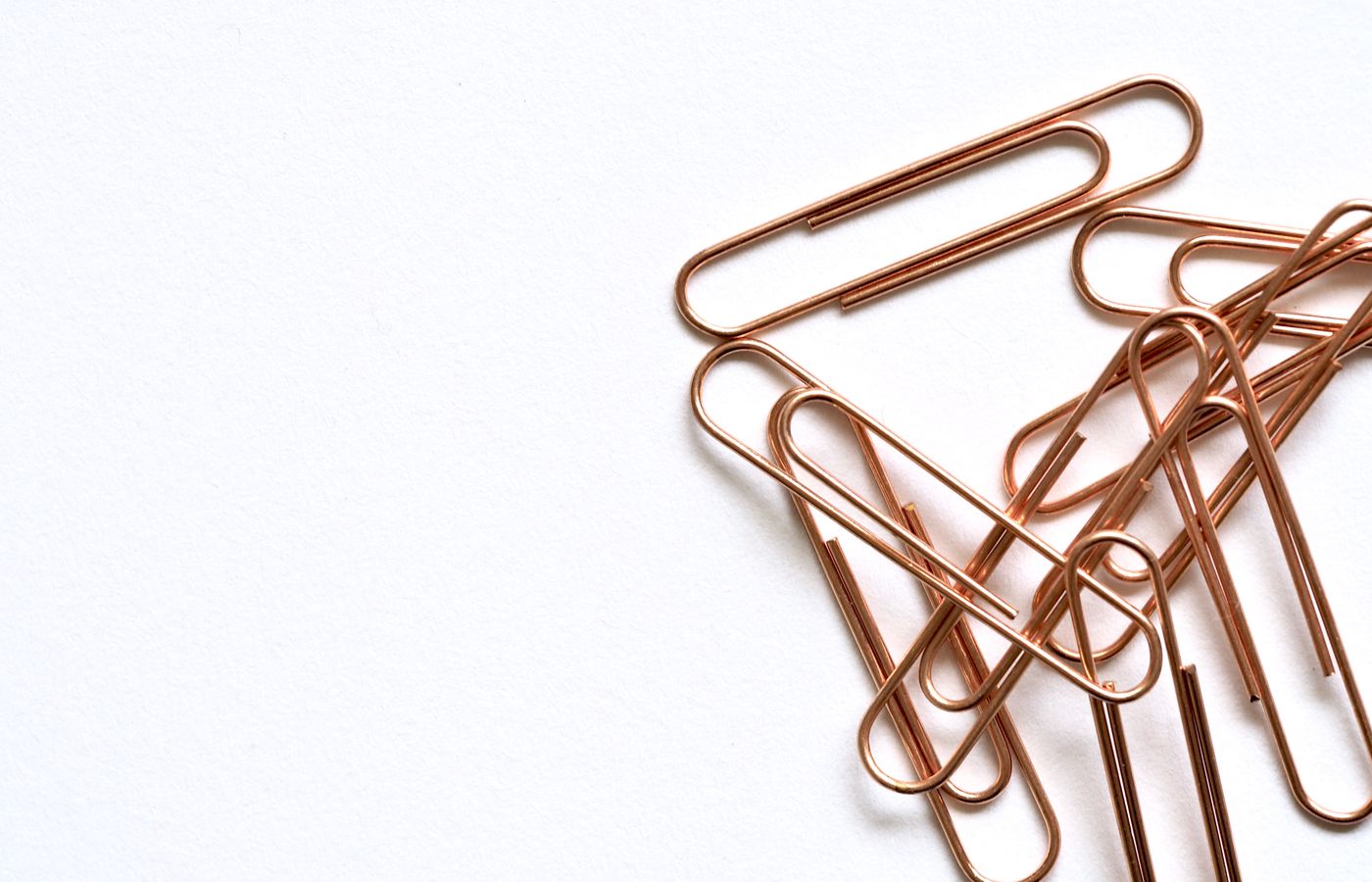 Copper paperclips arranged on a white background, highlighting modern office supplies.