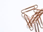 白色背景上排列的铜制回形针，突显了现代办公用品的特点