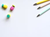 自上而下视角下，白色背景上排列着彩色笔和橡皮擦