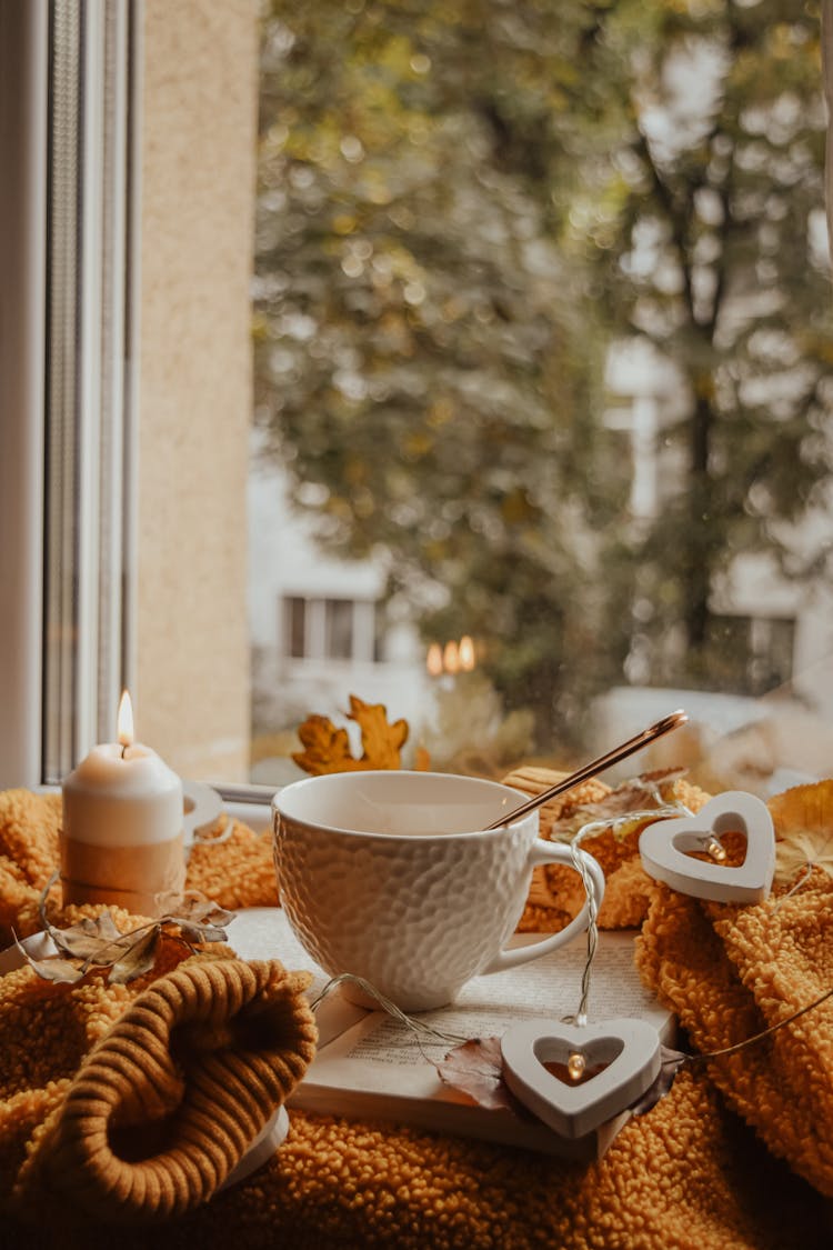 White Ceramic Teacup Beside A Lighted Candle