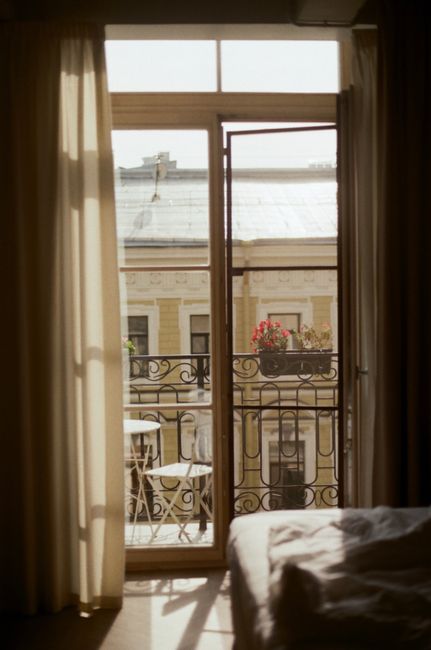 Sunlight streaming through an open window onto a balcony with flowers.