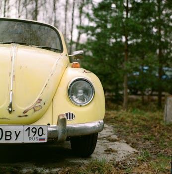 Rusty yellow Volkswagen Beetle parked outdoors, showcasing classic retro style and nostalgia.