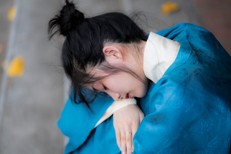 A Girl In Blue Robe With Messy Bun Sleeping On Her Arm