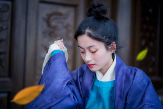 Portrait of a young woman in traditional Asian attire, set against a wooden carved background.