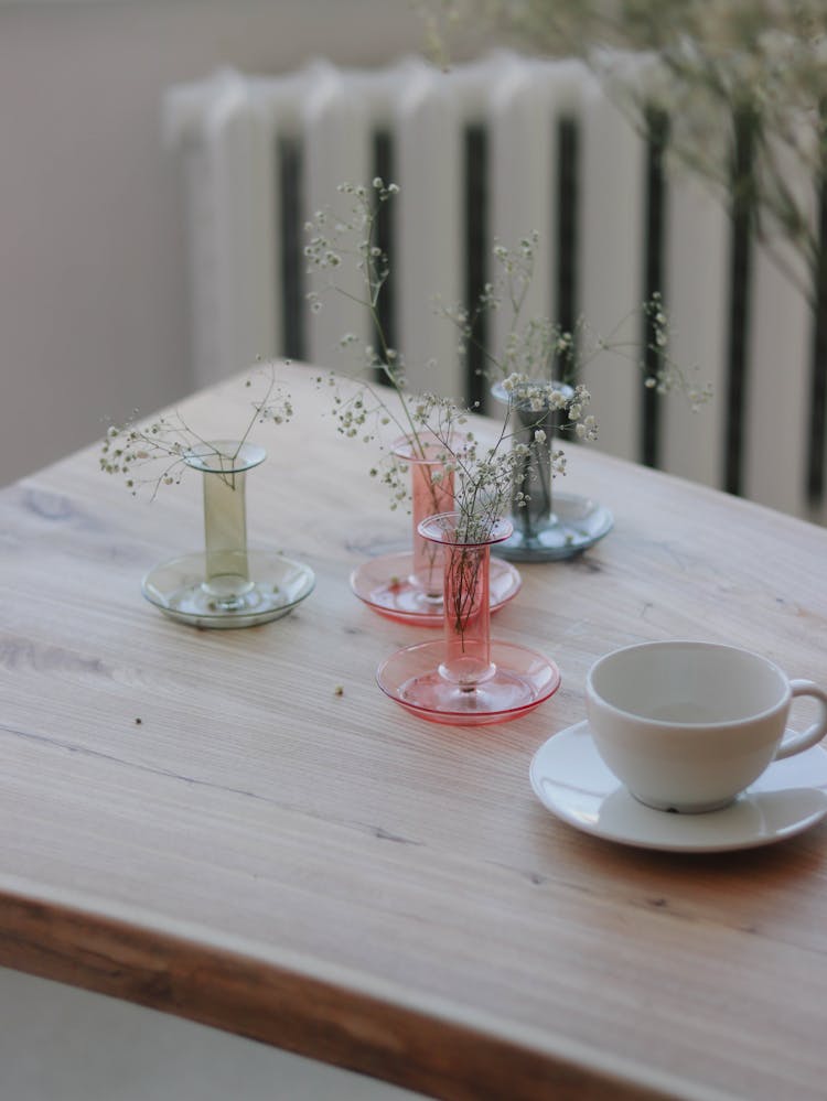 Floral Minimalist decoration In Glass Candlesticks and Empty Cup On Table