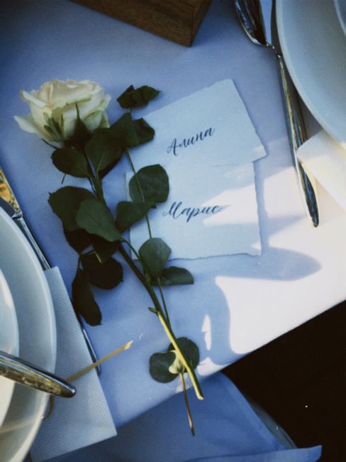 An elegant table setup featuring a white rose with personalized name cards on a dining table.