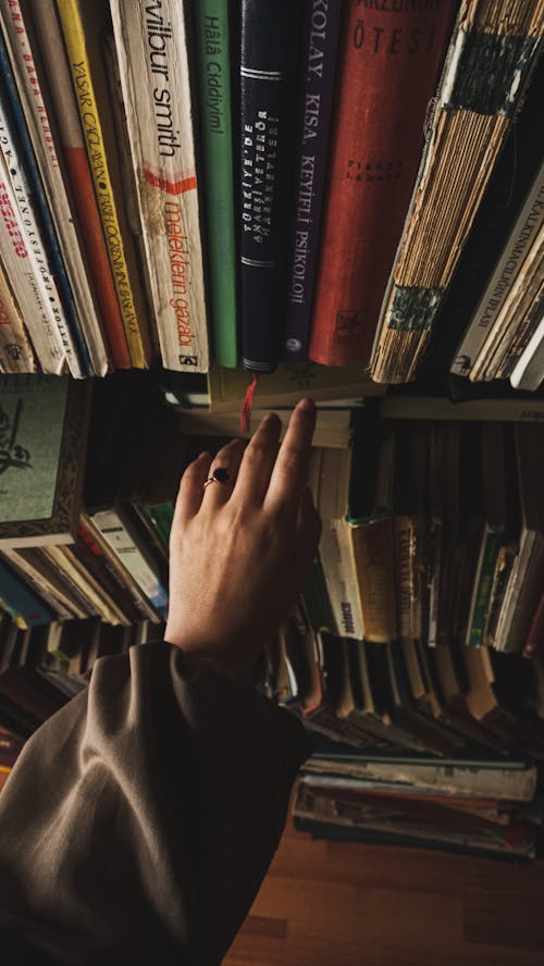 Hand of a Woman Reaching for a Book from a Shelf