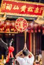 Man in Chinese street standing and holding thin candles in raised arms