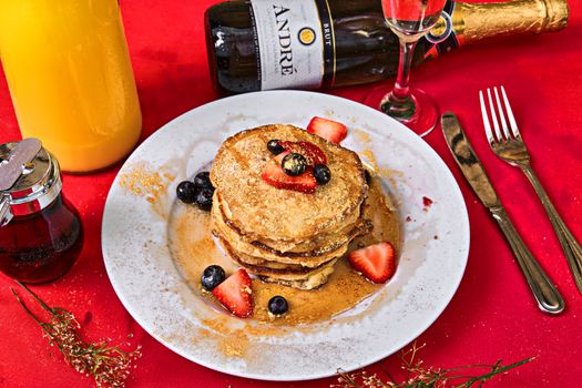 A stack of pancakes with strawberries and syrup, perfect for a delightful breakfast.