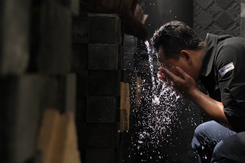 Man in Black Shirt Washing His Face