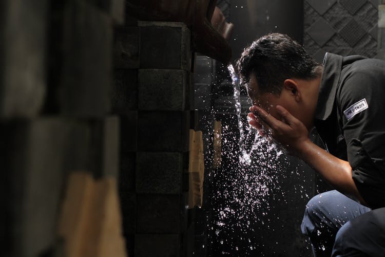 Man In Black Shirt Washing His Face