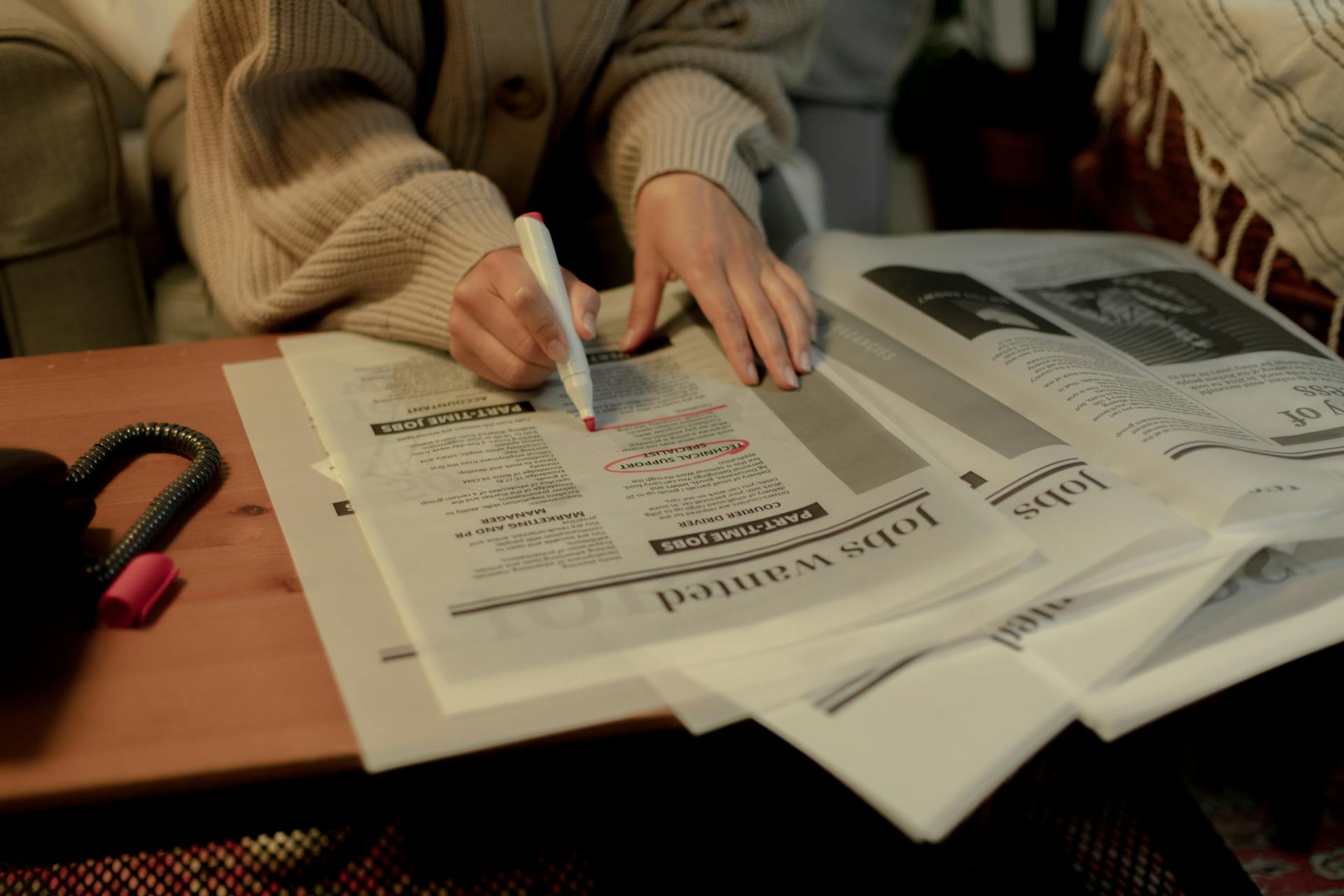 Close up on woman's hand while searching for job postings in newspaper