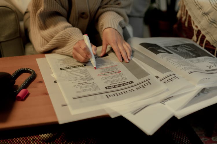 Close Up On Woman's Hand While Searching For Job Postings In Newspaper