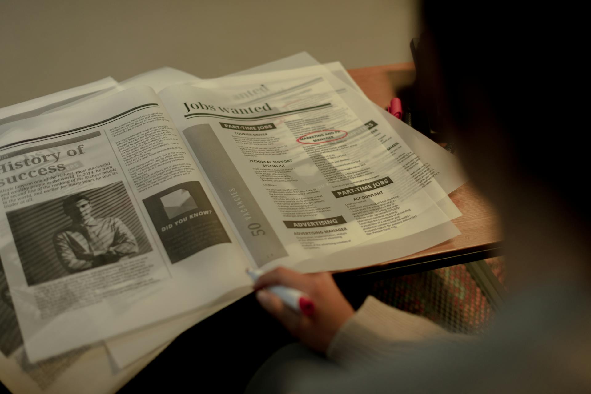 View from behind on woman reading newspaper with job postings