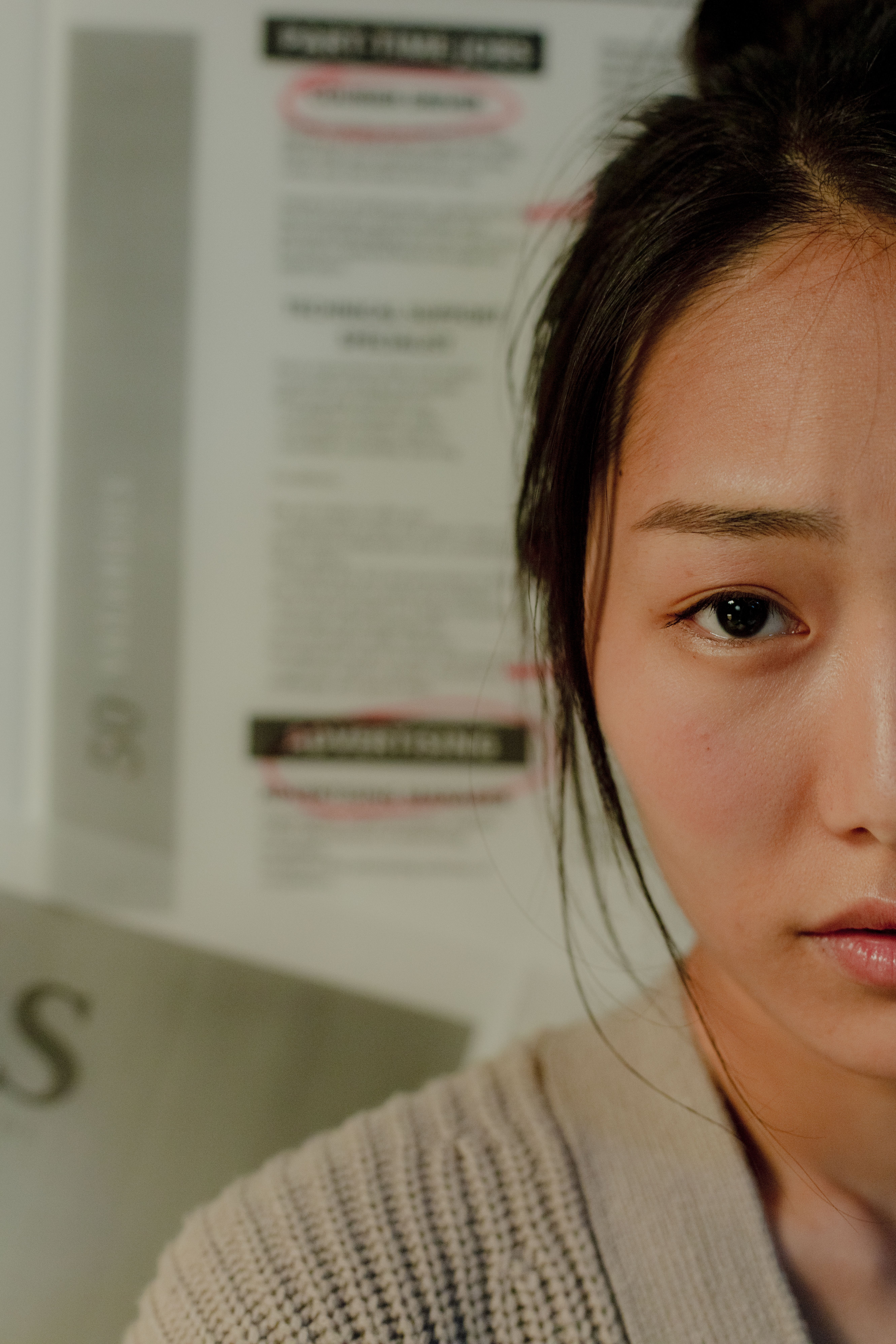 Emotive half-face close-up of an East Asian woman indoors, conveying a thoughtful mood.