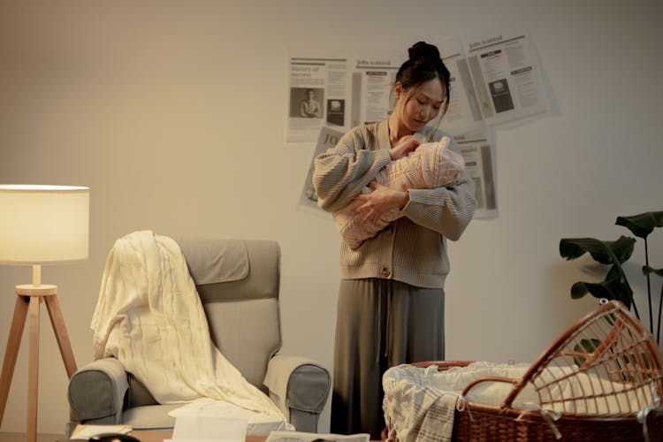 Woman Holding Newborn Baby In Hands And Looking At It