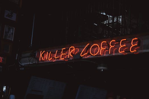 Bright neon sign 'Killer Coffee' in a dimly lit café setting.
