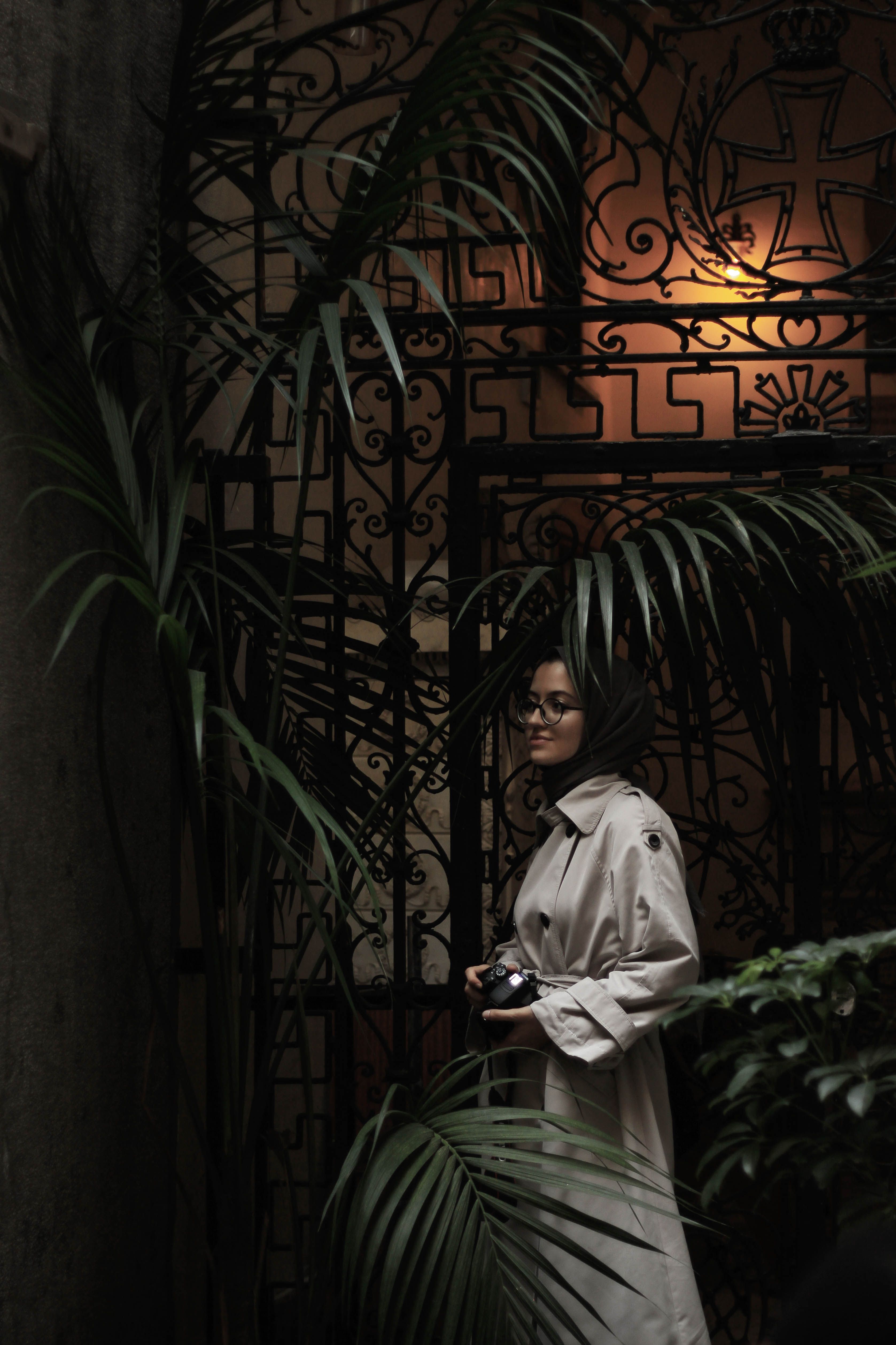Woman in Trench Coat Standing Beside Green Plant · Free Stock Photo