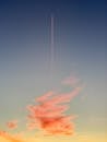Pink red cloud and airplane trail in evening sky
