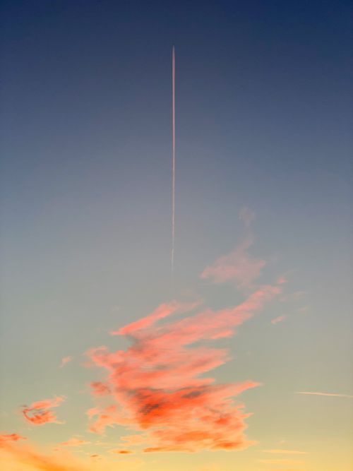 Free A serene sky with a vibrant contrail and pink clouds at sunset. Captivating aerial view. Stock Photo