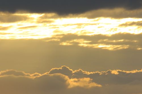 Free A stunning view of golden clouds backlit by the setting sun, creating a dramatic sky. Stock Photo