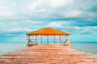 木制码头通向碧绿大海边的凉亭，天空生机盎然