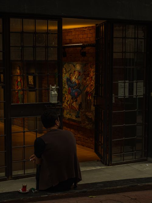 Free A man smoking outside a gallery with visible paintings, creating a moody vibe. Stock Photo