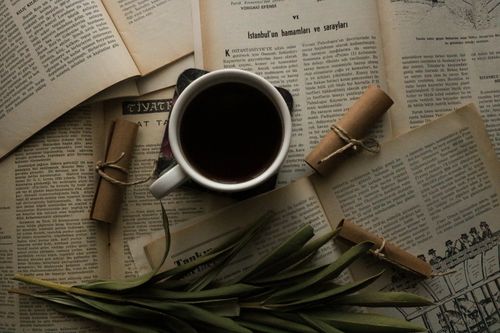 Free A cozy still life of coffee, old books, and rolled scrolls, perfect for readers. Stock Photo