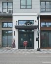 Woman in Red Coat Walking on Sidewalk Near Building