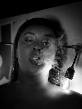 Striking monochrome portrait of a woman blowing smoke, emphasizing dramatic mood.