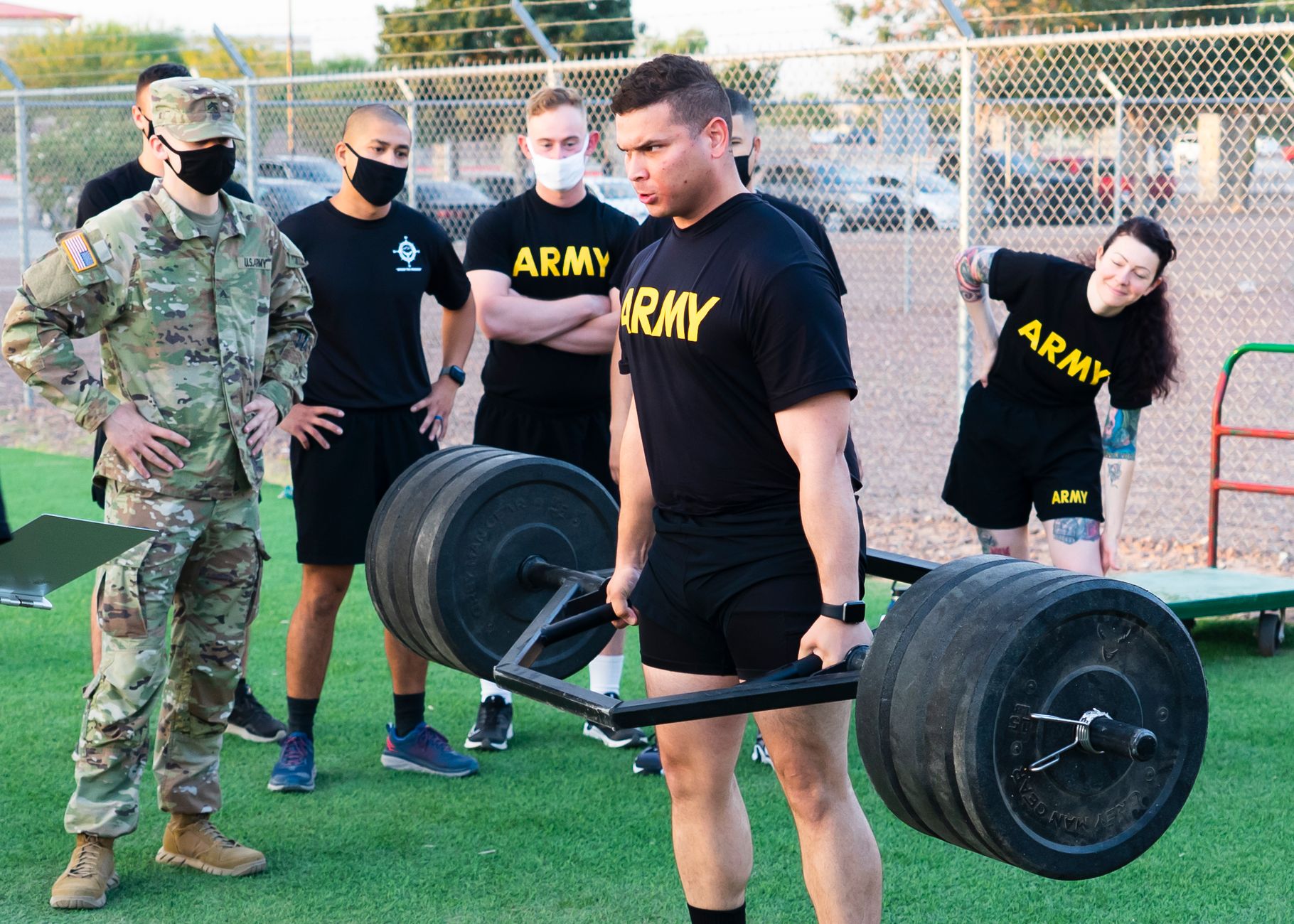 Army personnel participating in an outdoor weightlifting training session, showcasing teamwork and strength.
