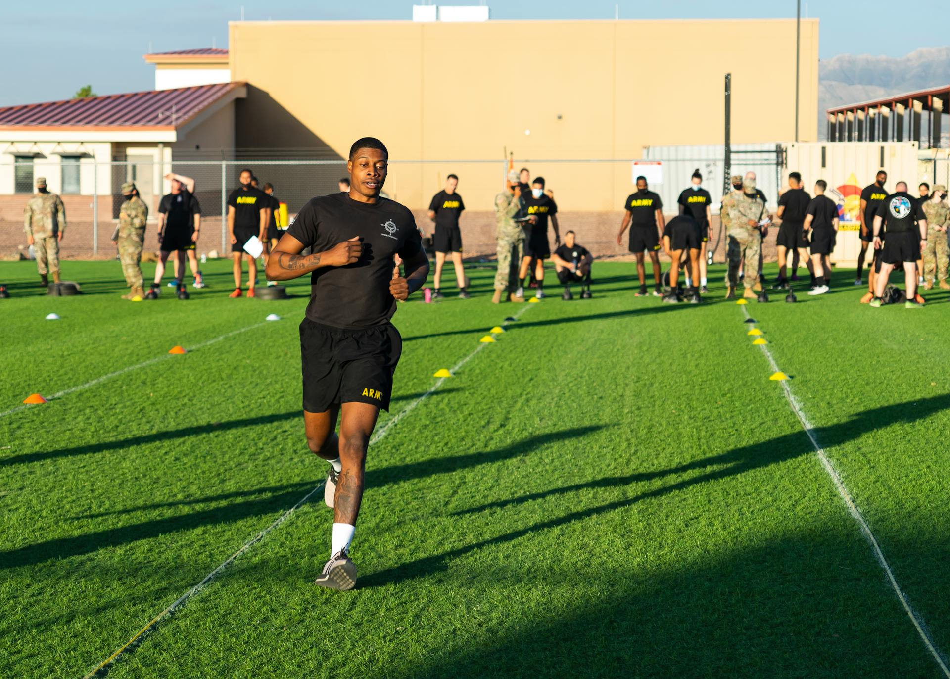 Participants engaging in a military fitness drill outdoors on a sunny day.