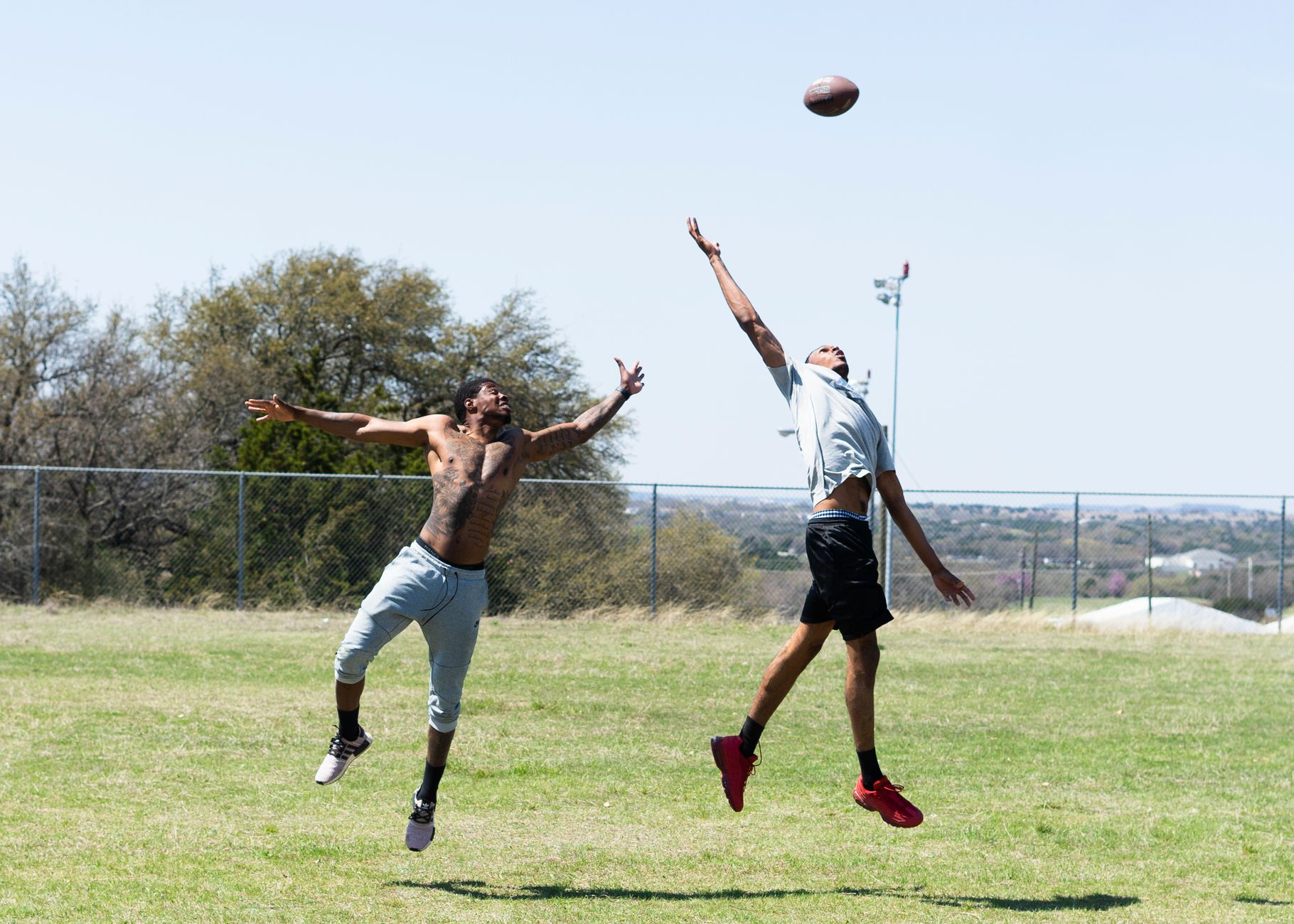 Two men catching a football during an outdoor game in Fort Hood, Texas.